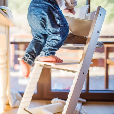 Baby klettert auf Hochstuhl