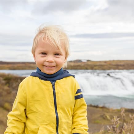 Süßer, blonder Junge vor einem Gletscher.