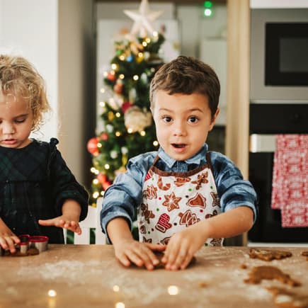 Ein Mädchen und ein Junge kneten zuckerfreien Plätzchen-Teig mit den Händen zur Weihnachtszeit.