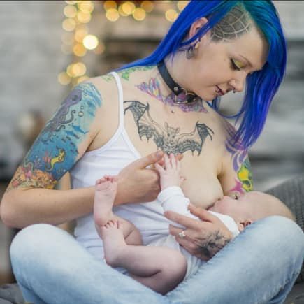 Tätowierte Frau stillt ihr Baby.