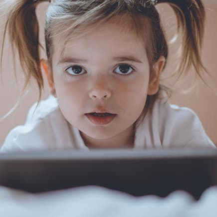 Kleines Mädchen mit Tablet im Bett.