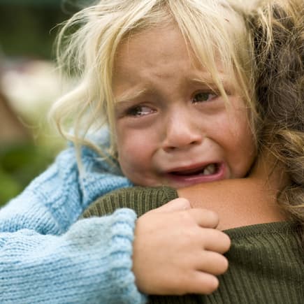 Mädchen bricht im Arm der Mutter in Tränen aus. 