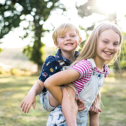 Mädchen trägt ihren Bruder Huckepack.