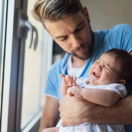 Junger Vater mit Baby auf dem Arm: Papas in Elternzeit müssen sich viele blöde Sprüche anhören.