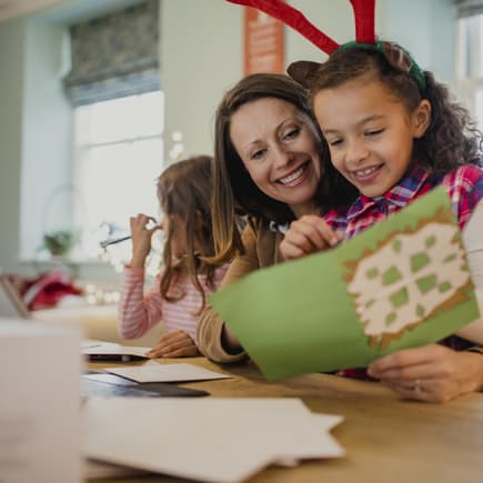 Mutter liest ihrer Tochter eine Karte mit Weihnachtsgrüßen vor.