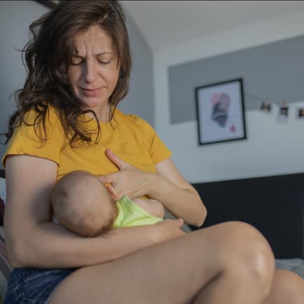 Mutter stillt ihr Baby und hat Schmerzen.