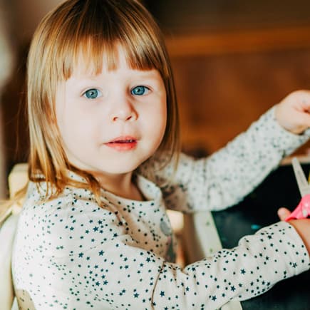 Kleines Mädchen übt mit der Schere das Schneiden