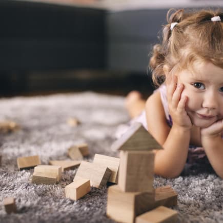 Kleines Mädchen spielt mit Holzbauklötzen.