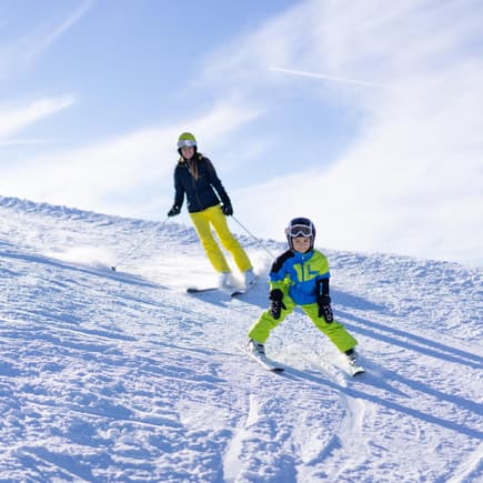 Eine Mutter bringt ihrem Sohn das Skifahren bei. 