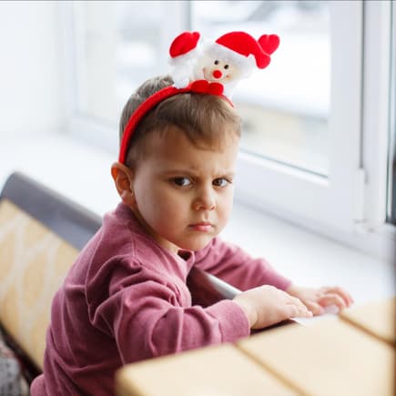 Ein Kind mit Weihnachtsmannhaarreif, der sauer gut