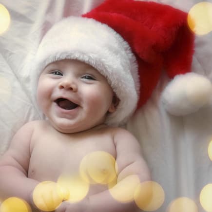 Lachendes Baby mit Weihnachtsmütze.