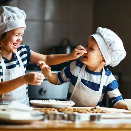 Zwei kleine, niedliche Kinder backen Kekse.