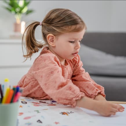 Kleines Mädchen klebt Sticker auf.