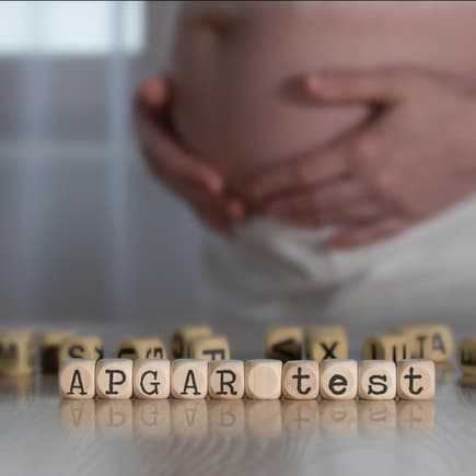 Schwangere Frau hinter dem Wort "Apgar-Test".