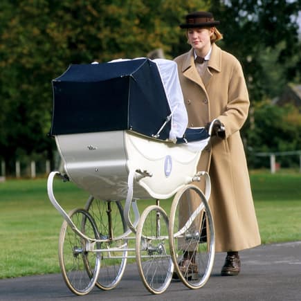Eine Norland-Nanny schiebt ein Baby im Kinderwagen draußen durch die Gegend.