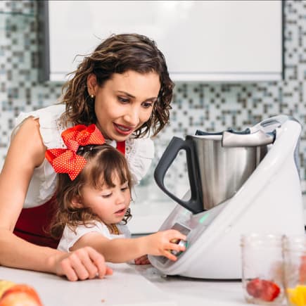 Mutter und Tochter bedienen eine Küchenmaschine.