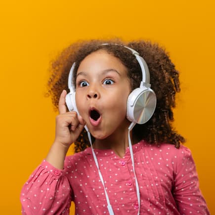 Kleines Mädchen hört begeistert Musik mit Kopfhörern.