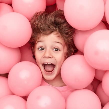 Aufgeregter Junge liegt in Luftballons.
