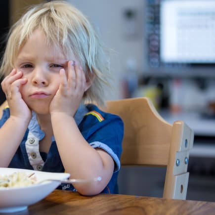 Kleiner, blonder Junge ist enttäuscht von seinem Essen. 