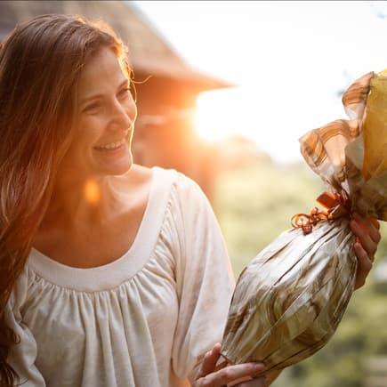 Eine Frau bekommt ein Ostergeschenk überreicht und freut sich.