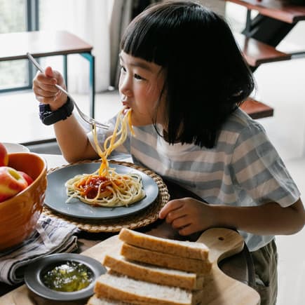 Mädchen isst Spaghetti.