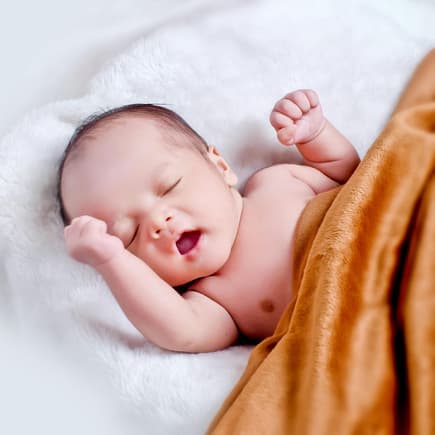 Baby, das auf weißem Fell mit brauner Decke liegt