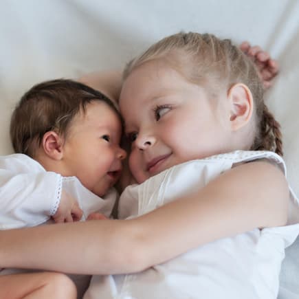 Mädchen hält Baby im Arm.