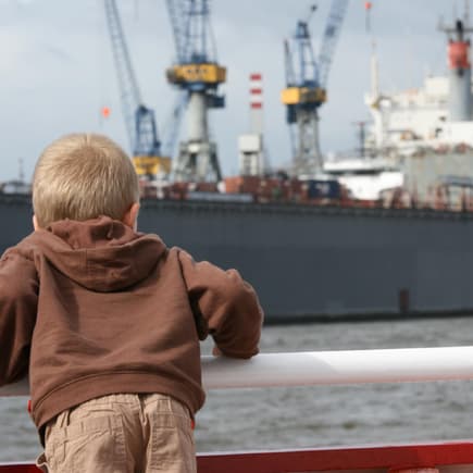 Junge bestaunt Schiff am Hamburger Hafen.