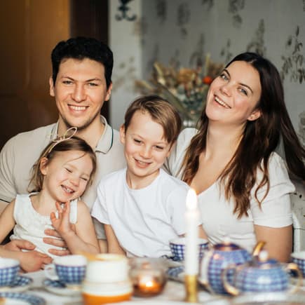 Eine glückliche, vierköpfige Familie ist abgebildet.