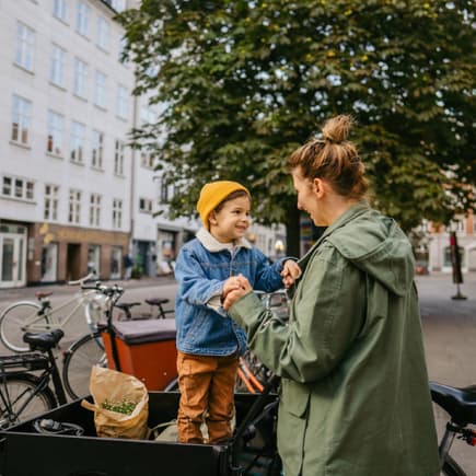 Ein kleiner Junge im Lastenrad mit seiner Mutter.