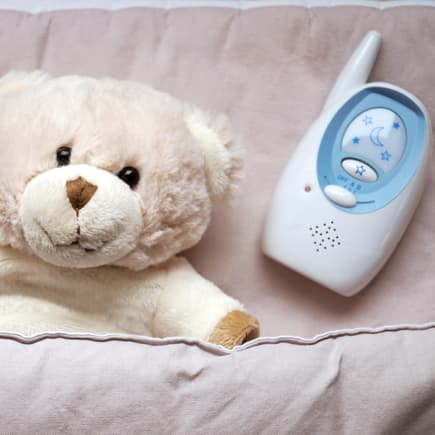 Ein Teddy liegt neben einem Babyphone. 
