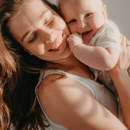 Glückliche Mutter mit süßem Baby auf dem Arm.