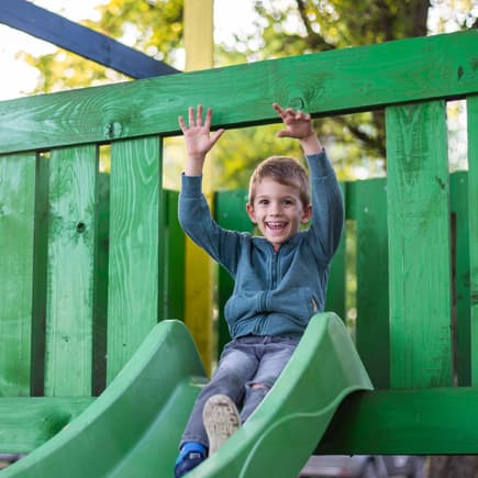Eine Junge auf einem Klettergerüst am Spielplatz. 