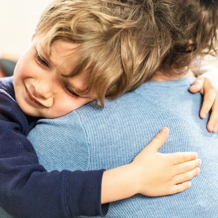 Ein kleiner Junge liegt weinend in den Armen seiner Mutter. 