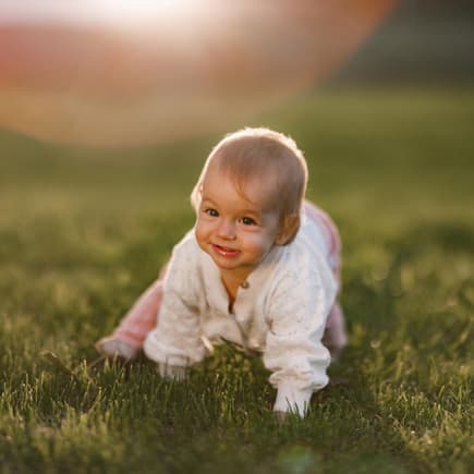 Ein Baby, das über eine Wiese krabbelt.