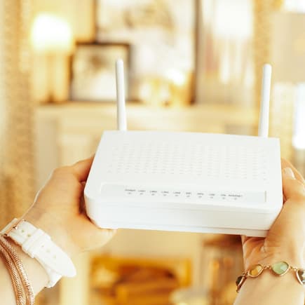 Frau hält einen WLAN-Router in der Hand.