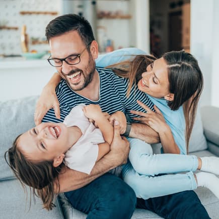 Fröhliche Familie tobt auf dem Sofa.