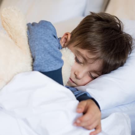 Junge liegt im Bett und schläft.