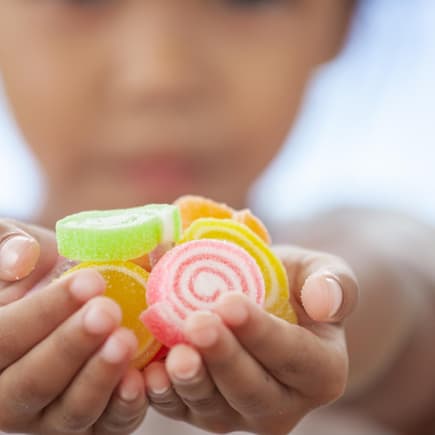Kind hält Fruchtgummis in der Hand.