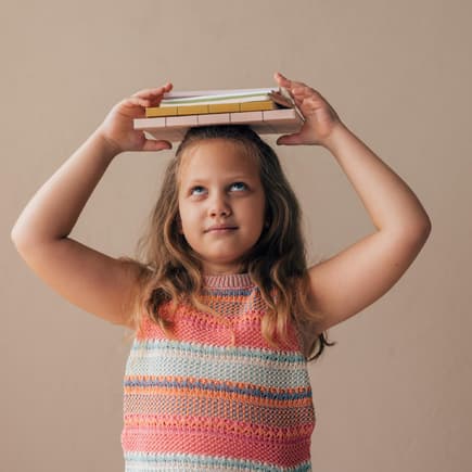 Mädchen balanciert Bücher auf dem Kopf.
