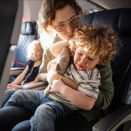 Eine Mutter tröstet ihr Kind im Flugzeug, das Ohrenschmerzen hat. 