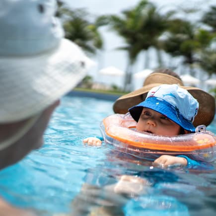 Baby mit Schwimmring um den Hals im Pool.