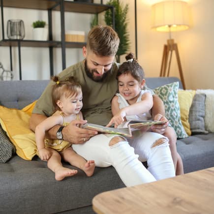 Vater schaut sich mit zwei Kindern Fotoalbum an.