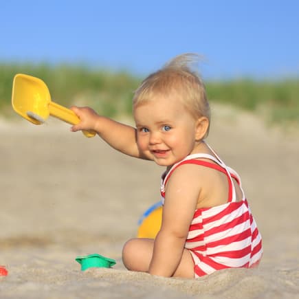 Ein Baby, das am Strand buddelt. 