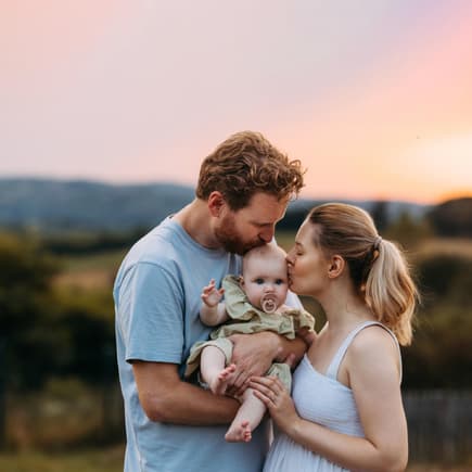 Mama und Papa mit Baby im Sonnenuntergang.