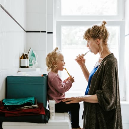 Mutter und Kind putzen gemeinsam die Zähne.