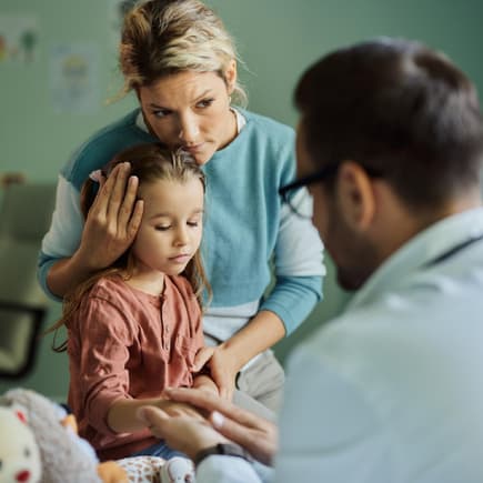 Eine Mutter und ein Vater trösten ihre kranke Tochter.