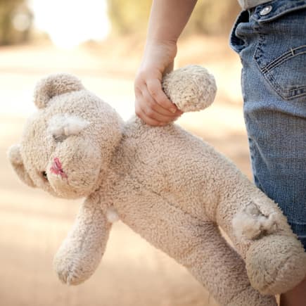 Ein Kind, das einen zerfetzten Teddy hält.