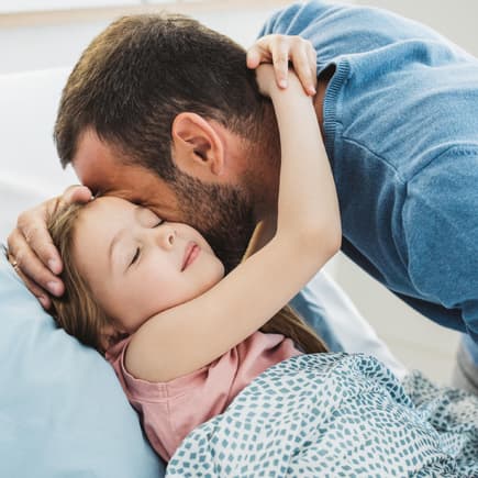 Kind umarmt seinen Vater beim Ins-Bett-Gehen.