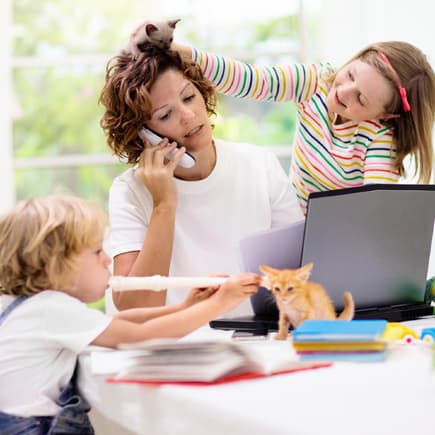 Mutter am Laptop wird von zwei Kindern genervt.